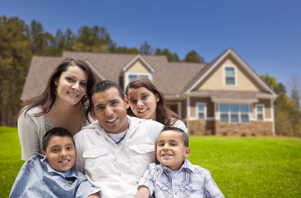 Happy Young Hispanic Family in Front of Their New Home